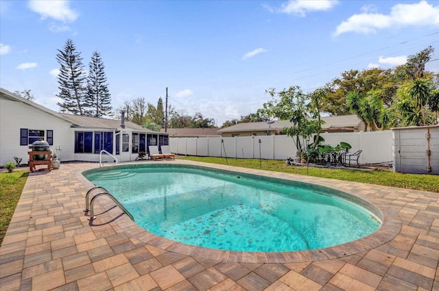 view of swimming pool featuring a sunroom, a patio, a fenced backyard, and a fenced in pool