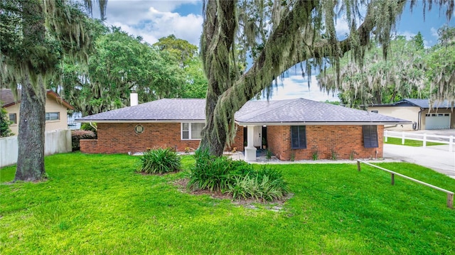 ranch-style house featuring fence, a front yard, a garage, brick siding, and a chimney