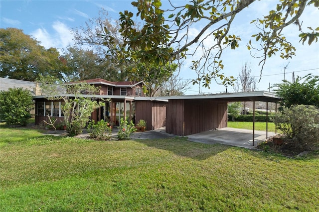 back of house with a carport and a lawn