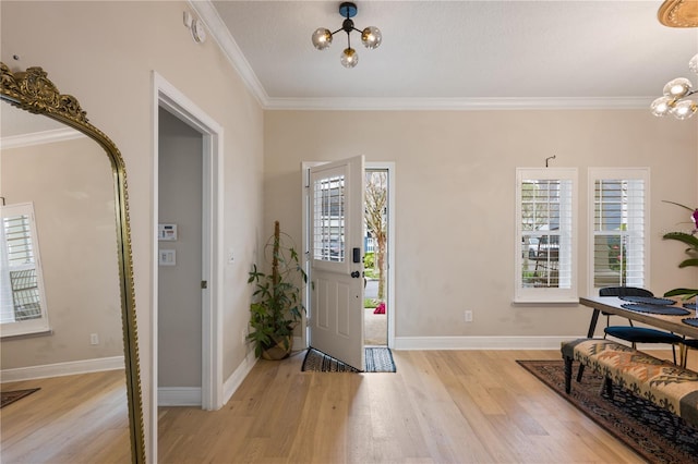 foyer with baseboards, ornamental molding, light wood-style flooring, and an inviting chandelier