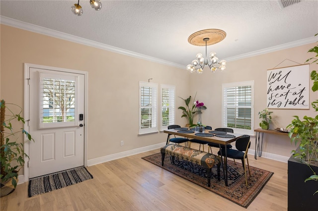 dining space featuring light wood-type flooring, an inviting chandelier, ornamental molding, and a textured ceiling