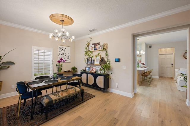 dining area with crown molding, visible vents, light wood-style flooring, a textured ceiling, and a chandelier