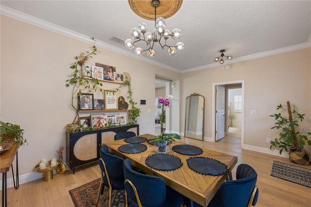 dining space featuring a chandelier, visible vents, light wood-style floors, and crown molding