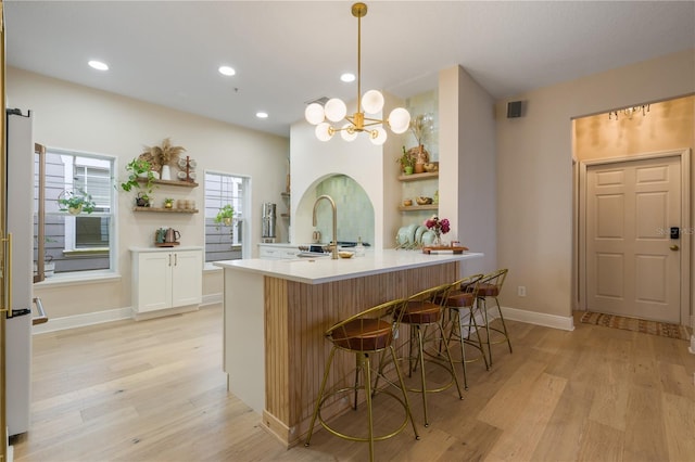 kitchen featuring white cabinets, a breakfast bar area, open shelves, and pendant lighting