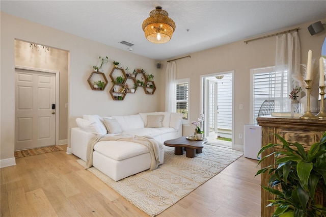 living area with baseboards, visible vents, and light wood-style floors