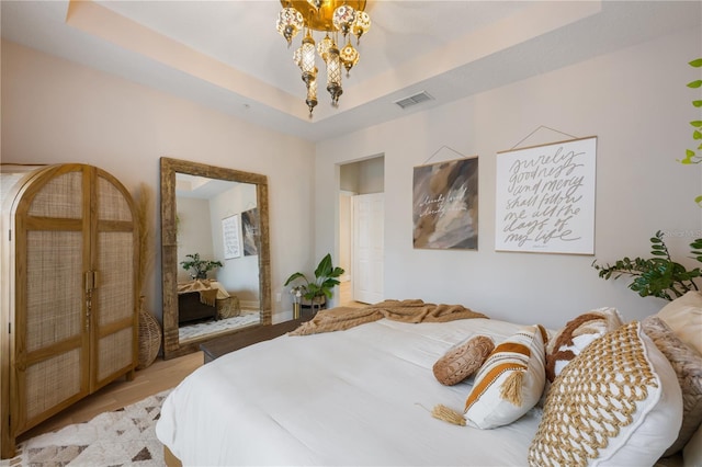 bedroom with visible vents, a raised ceiling, and a chandelier