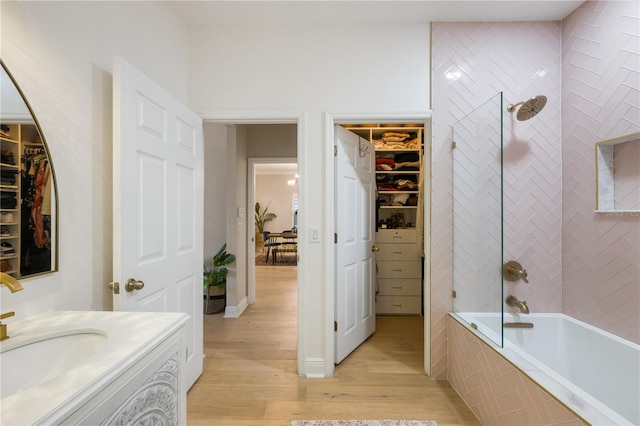 bathroom featuring tiled shower / bath combo, wood finished floors, vanity, and a walk in closet