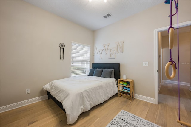 bedroom featuring wood finished floors, visible vents, and baseboards