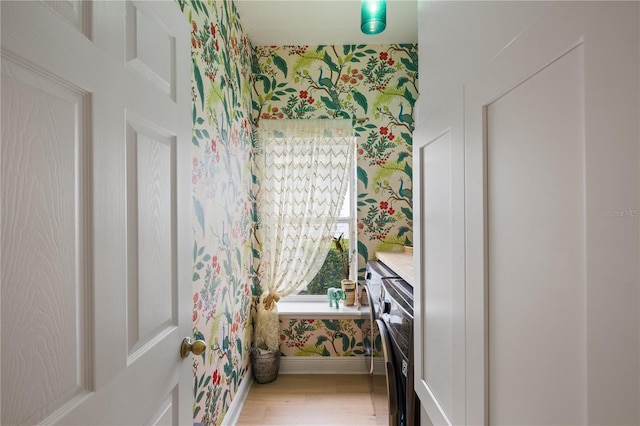 interior space with baseboards, wood finished floors, and wallpapered walls