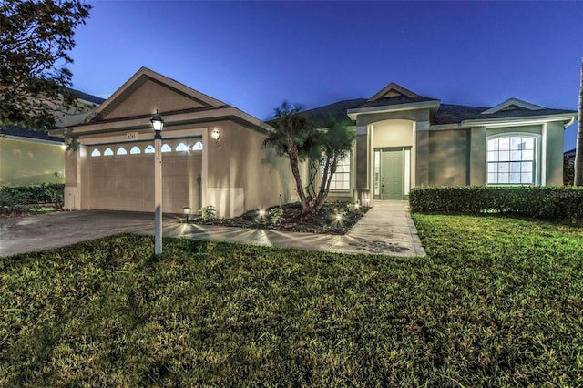 single story home with a garage, a yard, driveway, and stucco siding