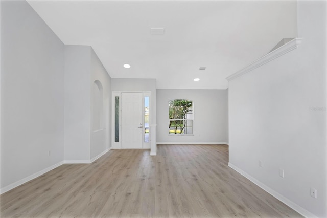 interior space featuring arched walkways, recessed lighting, light wood-type flooring, and baseboards