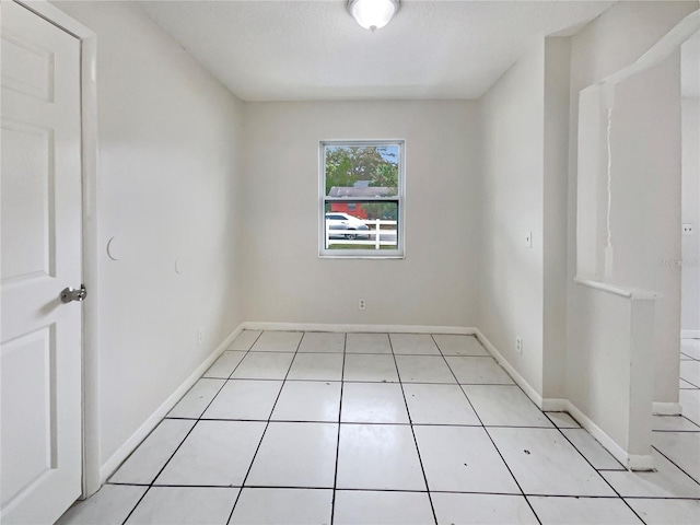 spare room featuring baseboards and light tile patterned flooring