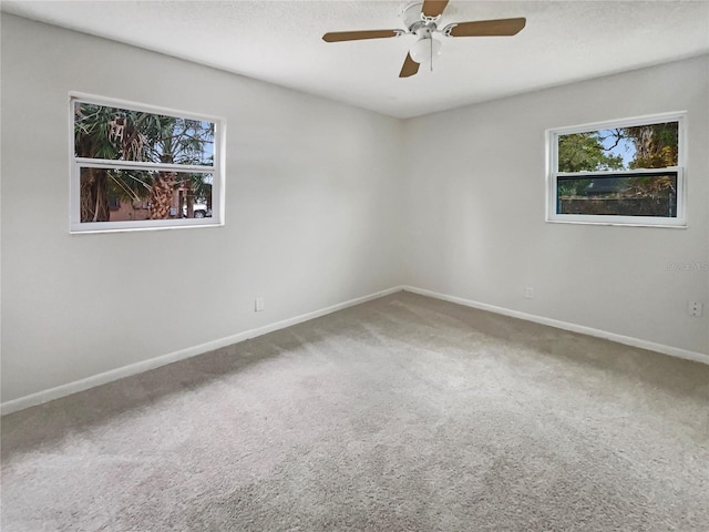 carpeted empty room with ceiling fan, baseboards, and a textured ceiling