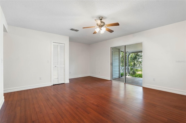 empty room featuring hardwood / wood-style flooring, baseboards, visible vents, and a textured ceiling