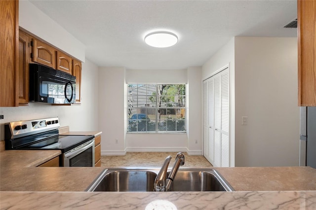 kitchen featuring black microwave, a sink, visible vents, stainless steel electric range, and brown cabinetry