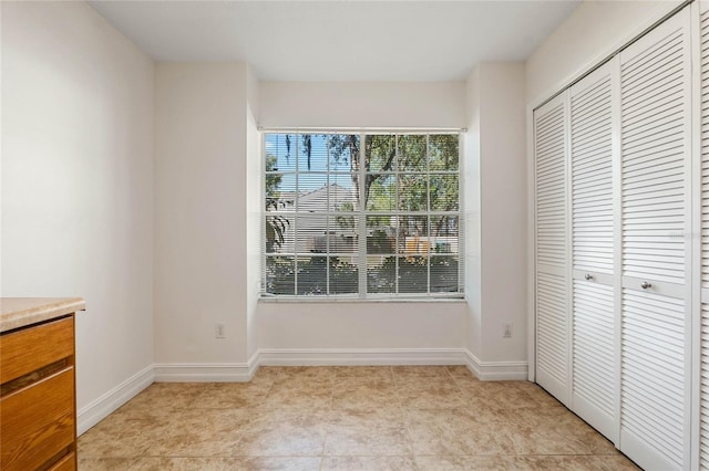 unfurnished bedroom with a closet, baseboards, and light tile patterned floors