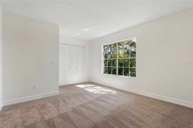 unfurnished bedroom featuring carpet floors, a closet, a textured ceiling, and baseboards