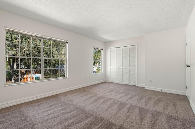 unfurnished bedroom featuring a closet, a textured ceiling, baseboards, and carpet flooring