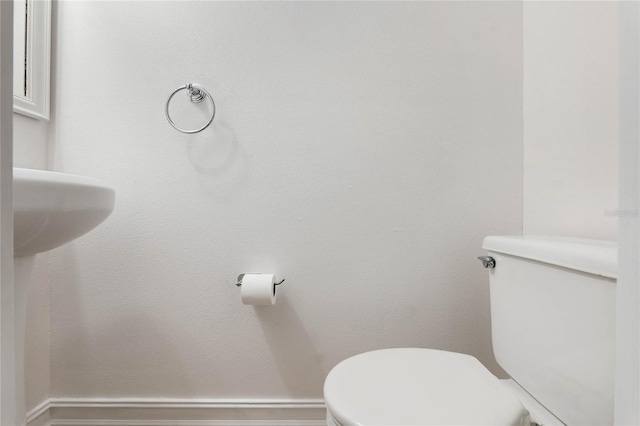 bathroom featuring baseboards and toilet