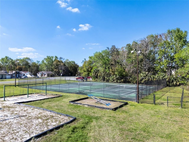 view of tennis court featuring a yard and fence