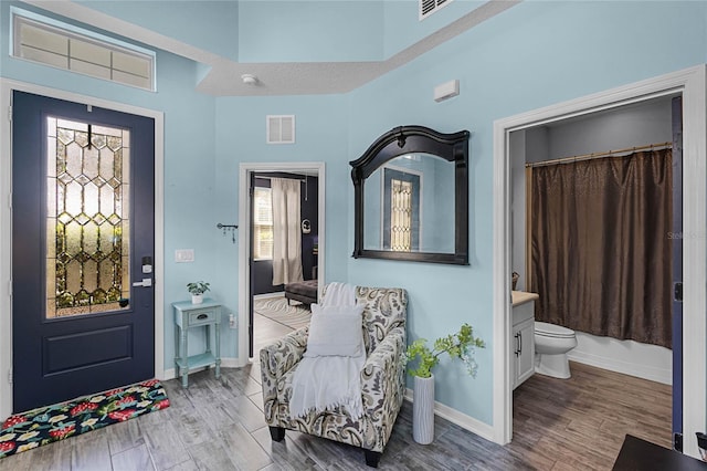 entryway with wood finished floors, visible vents, and baseboards