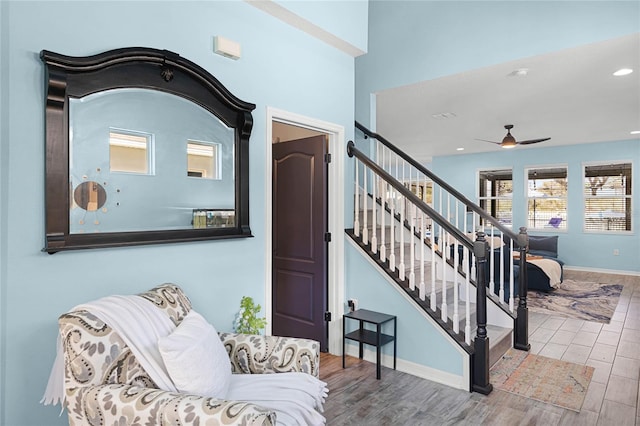 sitting room featuring a ceiling fan, stairway, baseboards, and wood finished floors