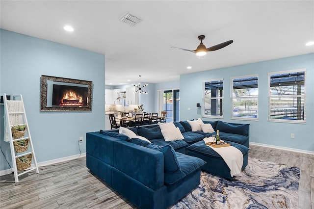 living room featuring baseboards, light wood-style flooring, visible vents, and a ceiling fan