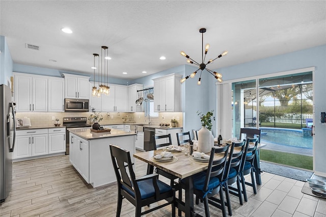 dining space with an inviting chandelier, visible vents, a textured ceiling, and recessed lighting