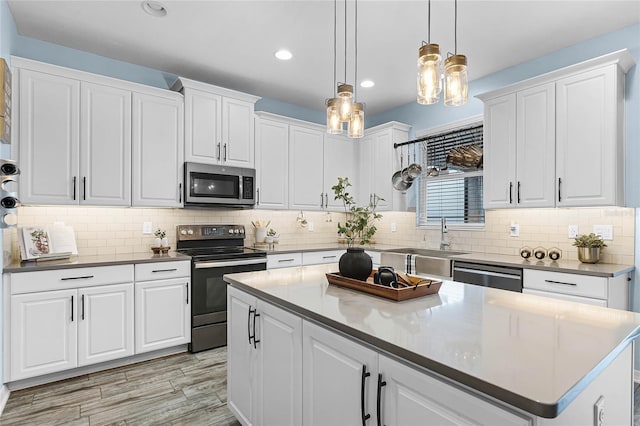kitchen with stainless steel appliances, decorative backsplash, white cabinetry, a sink, and a kitchen island