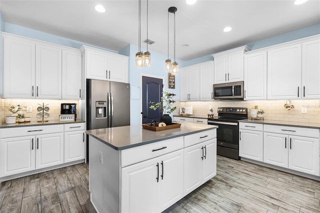 kitchen with stainless steel appliances, dark countertops, a kitchen island, and visible vents