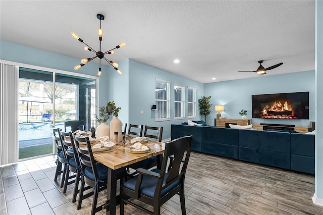 dining room with recessed lighting, ceiling fan with notable chandelier, a textured ceiling, and wood finished floors