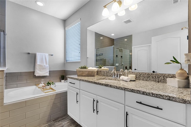 full bath with a stall shower, visible vents, wood finished floors, a garden tub, and vanity
