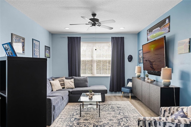 living room featuring ceiling fan, a textured ceiling, and wood finished floors