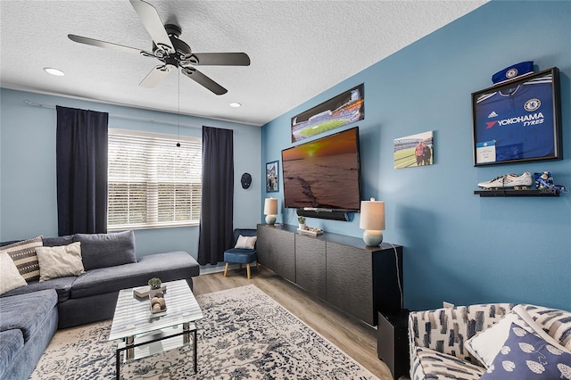 living area featuring a textured ceiling, a ceiling fan, and wood finished floors