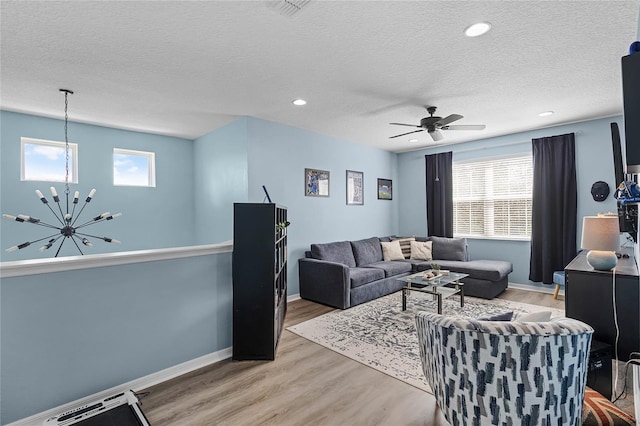 living area with baseboards, a textured ceiling, a wealth of natural light, and light wood-style floors