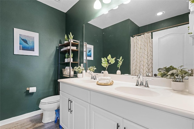 full bathroom with wood finished floors, a sink, toilet, and baseboards