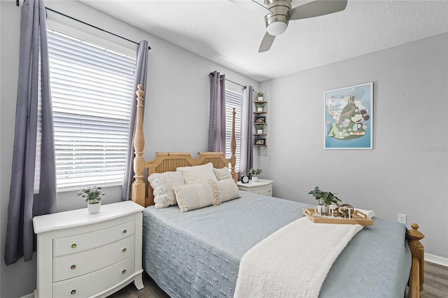 bedroom with dark wood-style floors, ceiling fan, baseboards, and a textured ceiling
