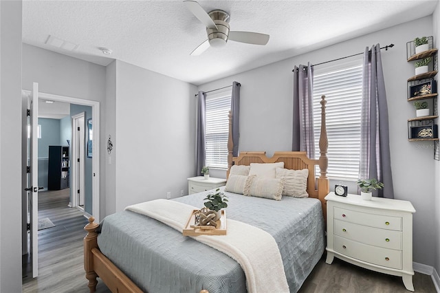 bedroom featuring a textured ceiling, ceiling fan, dark wood finished floors, and baseboards
