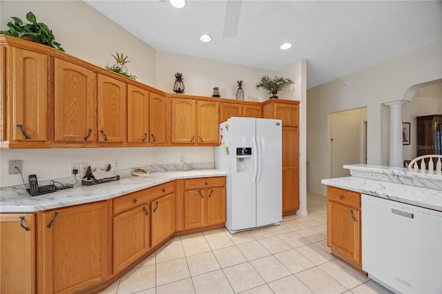 kitchen with white appliances, decorative columns, arched walkways, and brown cabinetry