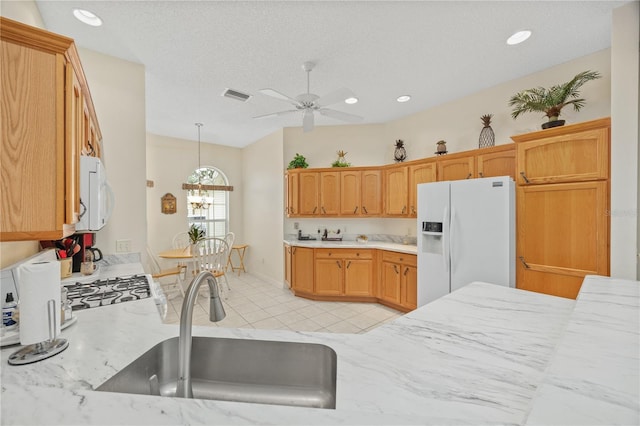 kitchen featuring white appliances, a sink, visible vents, light countertops, and hanging light fixtures