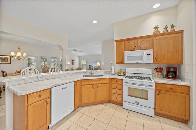 kitchen featuring light countertops, a sink, white appliances, a peninsula, and ornate columns