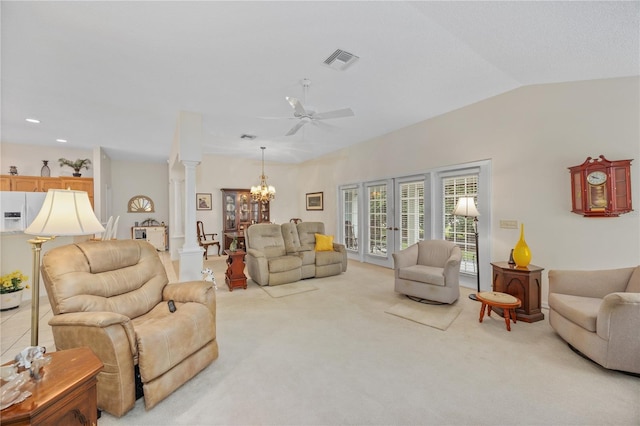 living area featuring lofted ceiling, visible vents, light carpet, ornate columns, and ceiling fan with notable chandelier