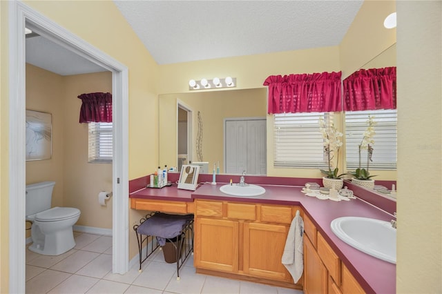 bathroom featuring toilet, double vanity, a sink, and tile patterned floors