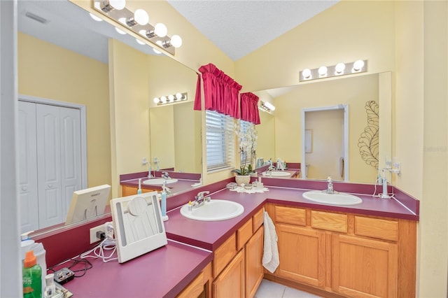 full bath with vaulted ceiling, double vanity, a closet, and a sink