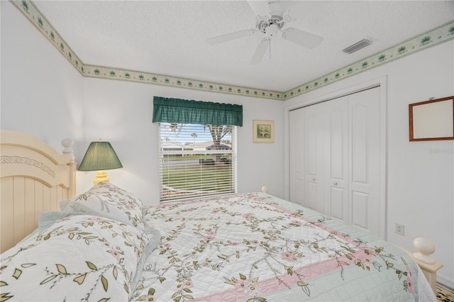 bedroom with ceiling fan, a textured ceiling, visible vents, and a closet