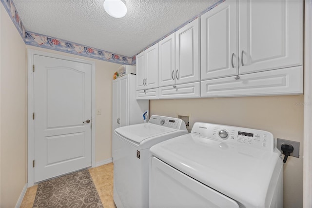 clothes washing area featuring washer and dryer, cabinet space, a textured ceiling, and baseboards