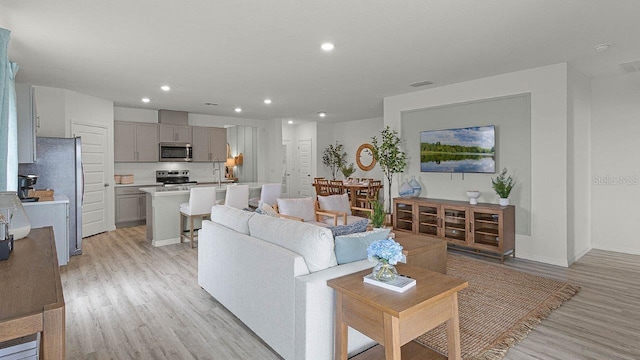 living room featuring light wood-type flooring, baseboards, and recessed lighting