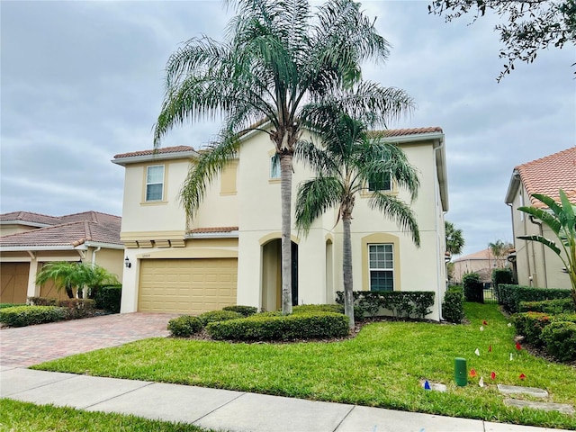 mediterranean / spanish home with a front yard, decorative driveway, a tiled roof, and stucco siding