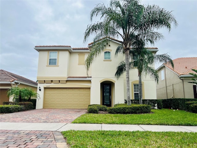 mediterranean / spanish home featuring a garage, a tiled roof, decorative driveway, and stucco siding