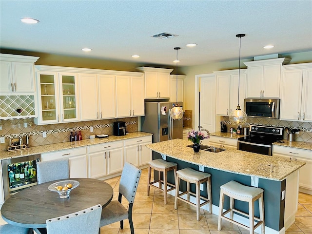 kitchen with light tile patterned floors, beverage cooler, a sink, appliances with stainless steel finishes, and a kitchen bar